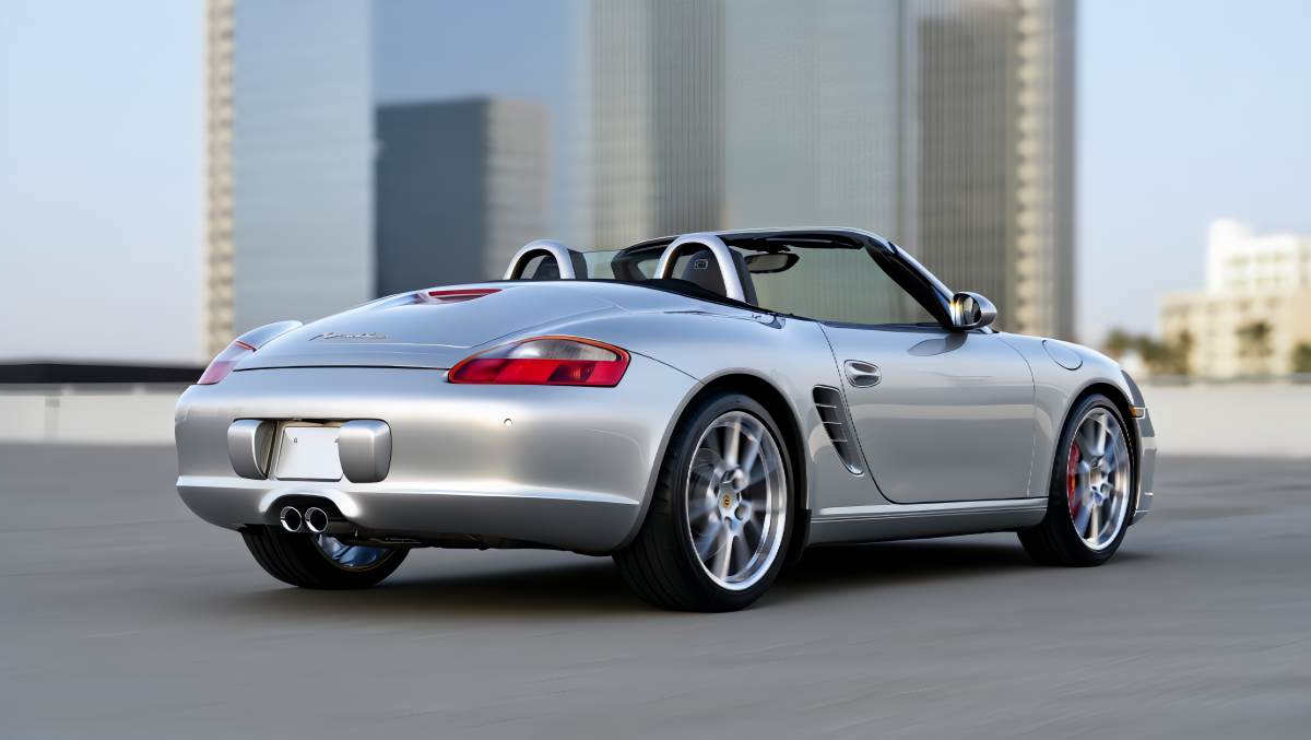 A silver Porsche Boxter sports car positioned in a modern urban environment with sleek glass buildings in the background