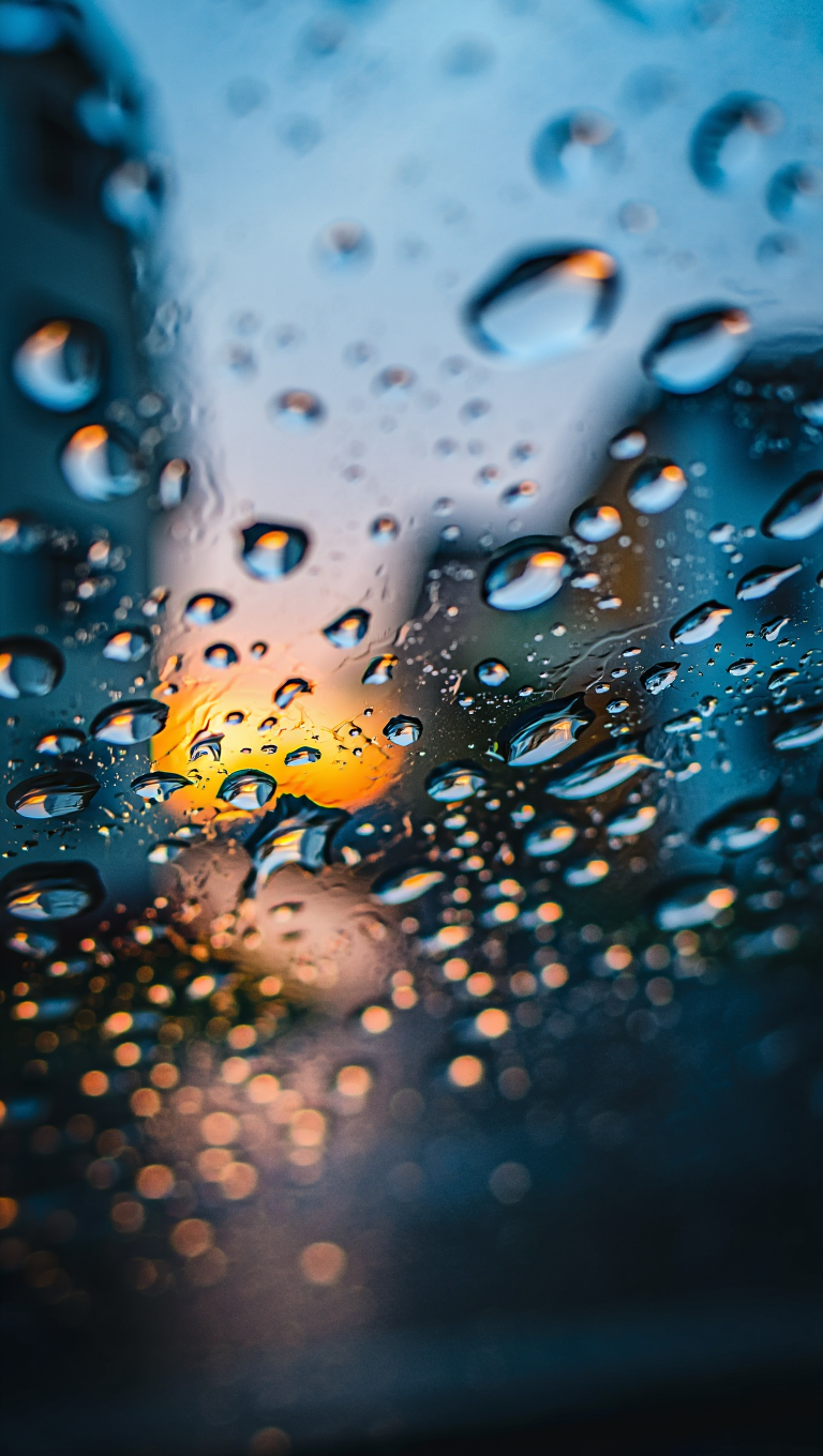 An extreme macro photograph of raindrops on a glass window or surface