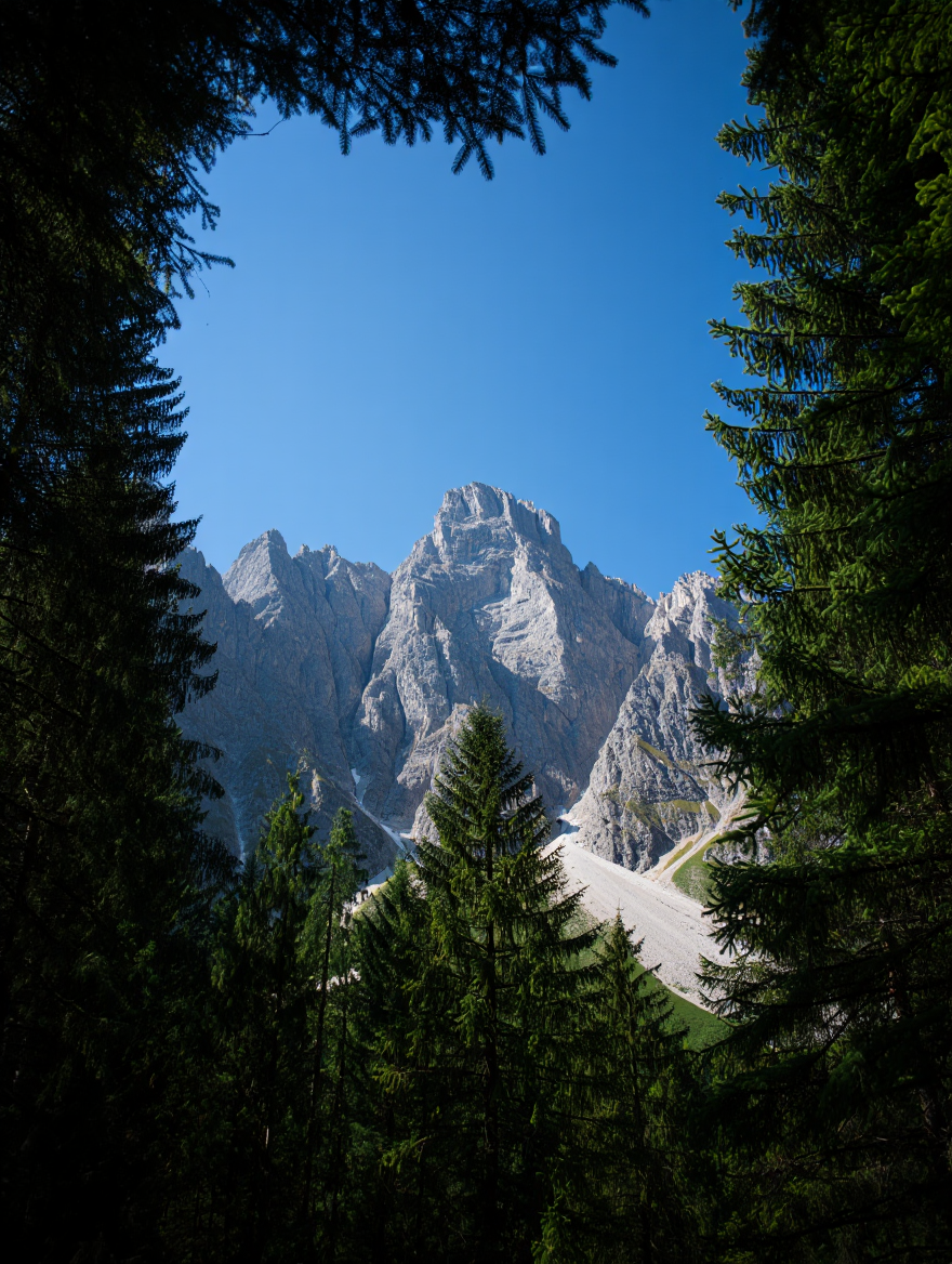 A majestic Alpine landscape photograph capturing a towering limestone mountain peak against a pristine blue sky