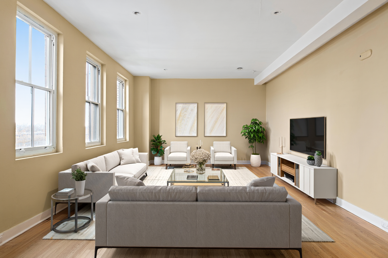 A modern living room features a large grey sectional sofa with white throw pillows positioned in the center of the room